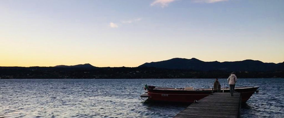 Barca ormeggiata a un pontile sul Lago di Garda al tramonto.