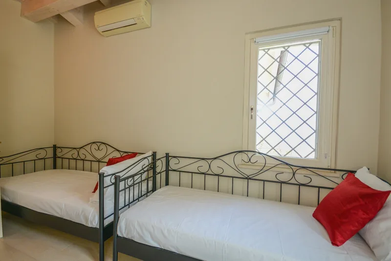 The two single beds with iron frames in the bedroom with exposed beams