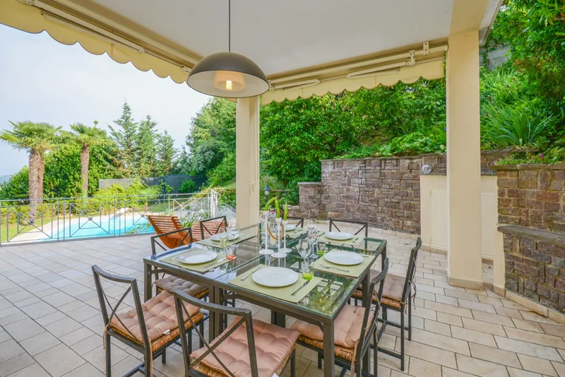Dining table under the covered terrace, overlooking the pool and garden