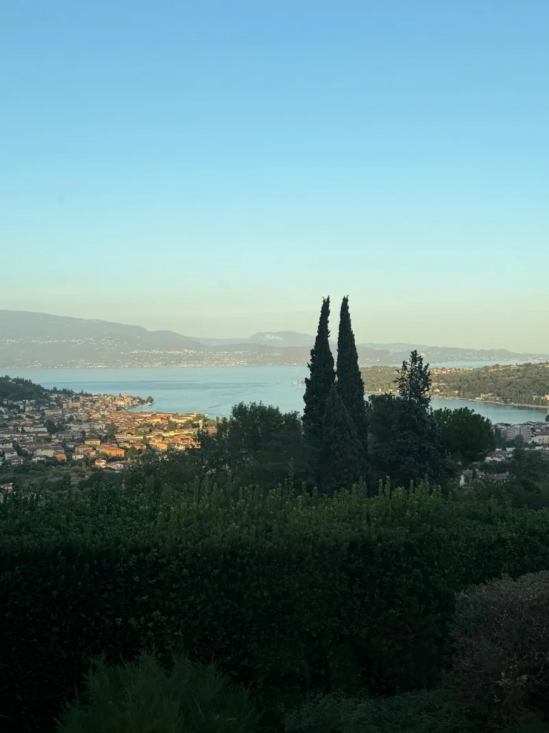 Cipressi e siepi del giardino davanti al panorama di Salò e del lago