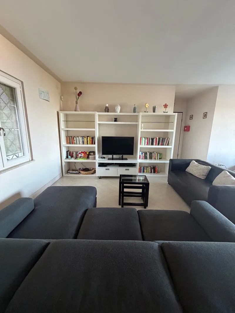 Living room with grey sofas, a television and white bookshelves